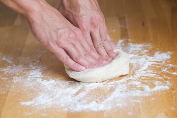 Man kneading dough and making pizza at home
