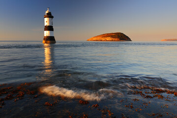 Fototapeta premium Penmon Lighthouse and Puffin Island on a calm summer evening. Anglesey, North Wales, UK.