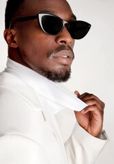 Closeup of handsome black man dressed in white with sunglasses on white background. Fashion Portrait