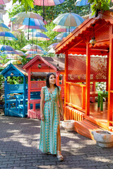 Obraz premium Woman posing in the foreground with colorful huts in the background and umbrellas hanging for shade and decoration.