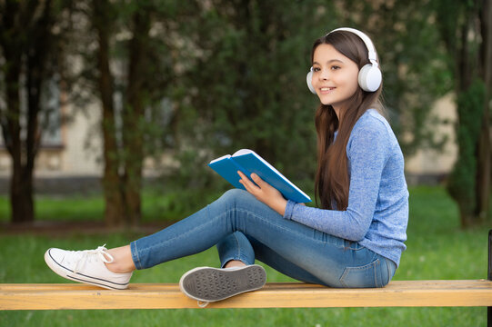 Concept Of Teen. Happy Teen Girl Reading And Listening To Audiobook In Headphones