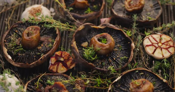 Grilling portobello mushrooms and seasoning with fresh herbs, close-up view