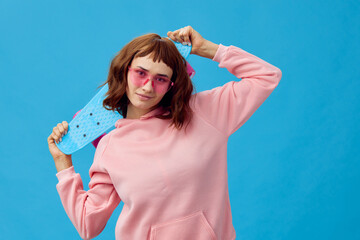 Happy cheerful pretty redhead lady in pink hoodie sunglasses with penny board posing isolated on...