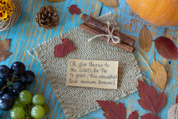 Handwritten text note to give thanks to the LORD on vintage wooden autumn background with grapes,...