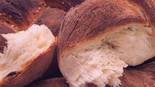 Shabbat challah bread with sesame seeds and raisins rotates in a circle on a wooden table. Close-up