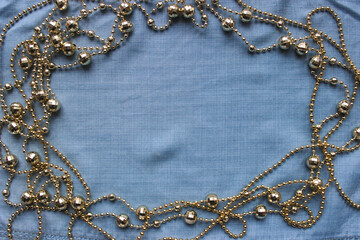frame of golden faceted beads garland on a blue background of denim fabric for a banner for the...