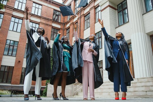 group of happy graduates throwing graduation hats in the air celebrating