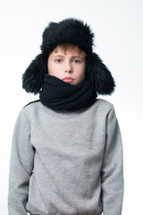 Portrait of a boy on a white background in a hat with ears and a scarf.