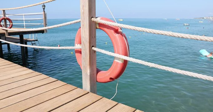 Orange life buoys on the mast against background of sea on sunny day
