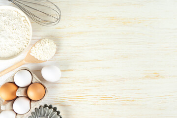 Fototapeta na wymiar Baking cooking Ingredients background with copy space. Flour, eggs, milk, bakeware on white wooden surface. Top view, flat lay. Mockup menu, banner, header for site, baking concept