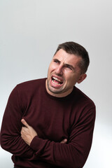 Fototapeta premium A man touches his stomach with two hands, on a white background with copy space, Stomach pain in a man.