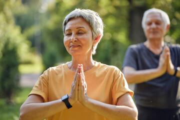 Older active couple do meditation practice outdoors - 530656107