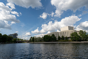View across the Brda River, of the Opera Nova building in Bydgoszcz and the Nordic Haven skyscraper, from the side of Mill Island   - obrazy, fototapety, plakaty