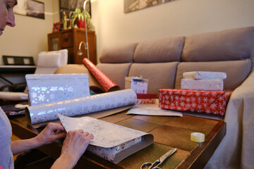 A Woman cutting out Christmas paper to wrap presents.