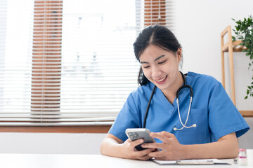 Veterinarian woman in blue uniform is using smartphone to searching pet information and writing data