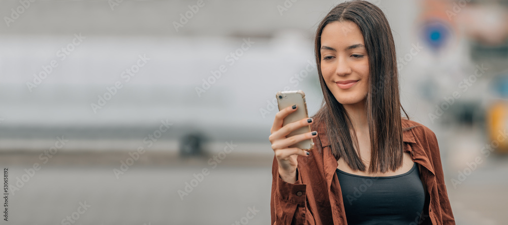 Wall mural girl looking at mobile phone or smartphone