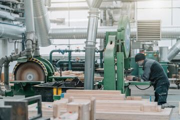 Unrecognizable worker inside huge woodwork factory workshop with stacks of wood.