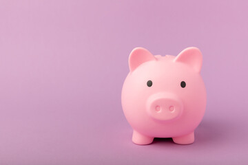 Piggy bank on a lilac texture background. Close-up. Space for copy. Flat lay. Savings and accumulation concept.