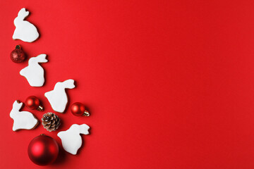 Delicious gingerbread in the form of a rabbit and Christmas decor on a red background. copy space. Symbol 2023
