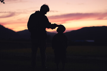 夕焼けを眺める親子のシルエット