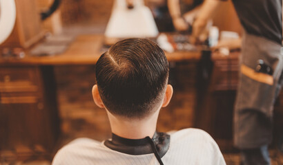Barbershop concept, vintage color. Closeup man haircut, master does hair styling in barber shop...