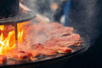 Chef cook prepares Beef steak is fried on open fire outdoor grill in shape of circle