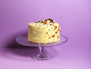 Festive banana cake in white chocolate, decorated with nuts, cookies and chocolate on a pink background. exclusive pastries, author's recipes. copy space. for a culinary blog and a pastry shop