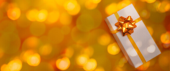    White gift textured box with golden bow on yellow bokeh lights background. Christmas, New Year,...