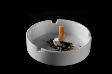 Cigarette stub, matches and ash in ashtray isolated on black, top view