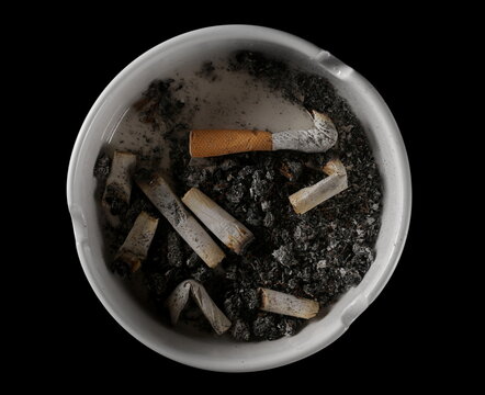 Cigarette stubs, matches and ash in ashtray isolated on white background, top view