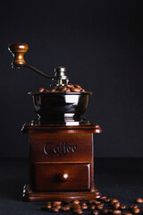 Coffee grinder with coffee beans on black background