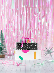 Hot pink Merry Christmas celebration minimal concept with gift boxes, green pine tree, ribbon and silver star decoration ornament. Iridescent holographic background. Festive 2023 New Year aesthetic.