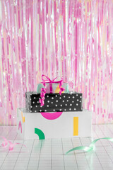 Girly colorful birthday party gifts minimal concept with vivid pink and green ribbon on a grid pattern. Iridescent holographic background. 2023 New year, Christmas celebration, present aesthetic.