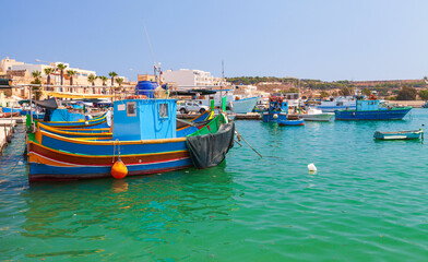 Fototapeta na wymiar Colorful Maltese fishing boats are moored in Marsaxlokk
