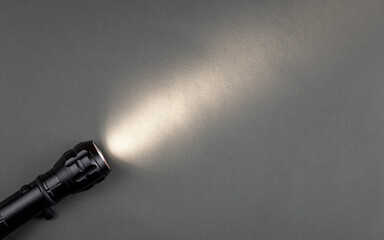 A bright beam of light from a flashlight shines on a gray background