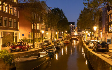 Typical old Amsterdam houses  and chanels with boats at night in Netherlatnds
