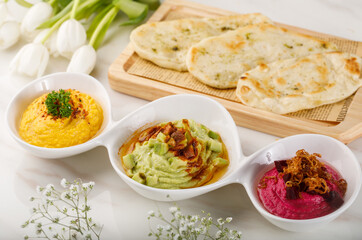 TRIO HUMMOS with pita bread served in a dish isolated on table side view of arabian food