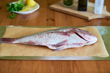 Process of cooking Dorado fish with olive oil and herbs. Female hands close-up.