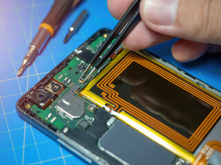Smartphone technician repairing the motherboard of a smartphone on service lab desk. Electronic...