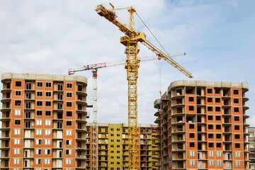 A tower crane works on the construction of a residential building. The concept of construction business.