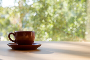 A cup of coffee is on the table near the window. Sunlight, coffee mood.