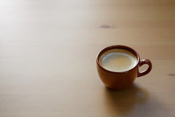 A cup of coffee is on a wooden table. Space for text.