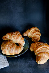 Delicious breakfast with fresh and baked french croissants on a dark concrete background