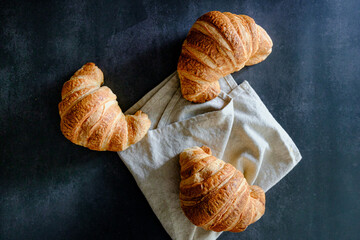 Delicious breakfast with delicious and fresh croissants on a dark concrete background. Top view. 