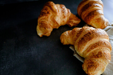 Delicious breakfast with fresh and baked french croissants on a dark concrete background. Space for text