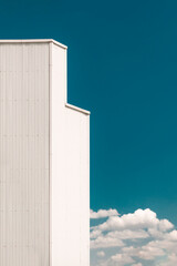 Industrial warehouse facade with white roof and nearby trees