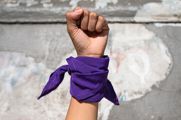 Mano de mujer feminista con pañuelo morado en la calle. 