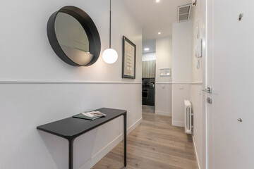 Hallway of a vacation rental home with black designer sideboard and matching circular mirror