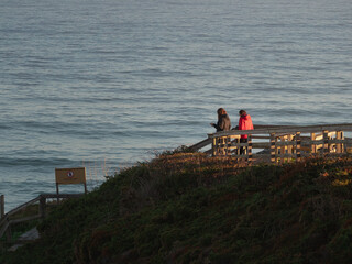 Two women watching the ocean at sunset