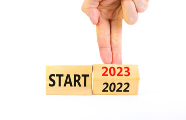 2023 start new year symbol. Businessman turns a wooden cube and changes words Start 2022 to Start 2023. Beautiful white table white background, copy space. Business 2023 start new year concept.